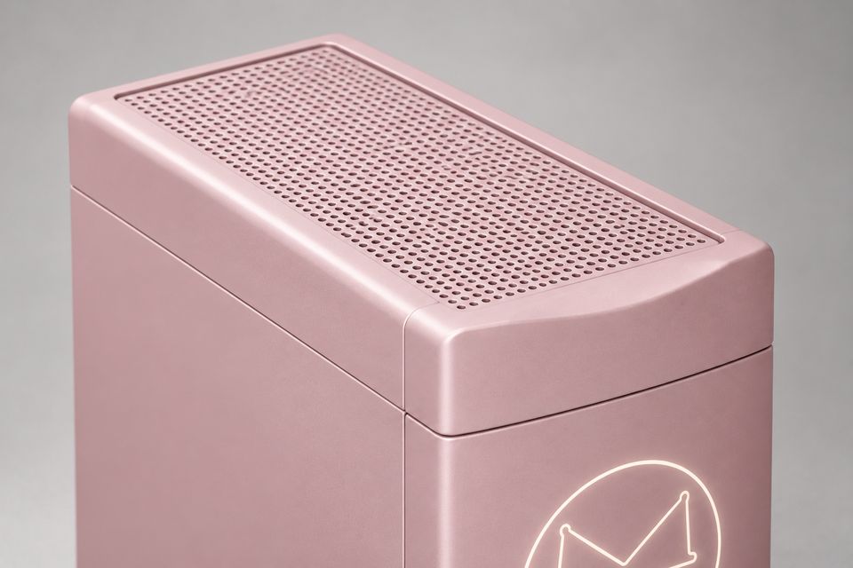 Close-up of the Spine concept in Blush Pink, looking down at its top: an evenly perforated grille framed by a rounded rim, and a separate top cap whose front edge curves gently inward. Part of the glowing outlined Synkurl mark shows on the front below.